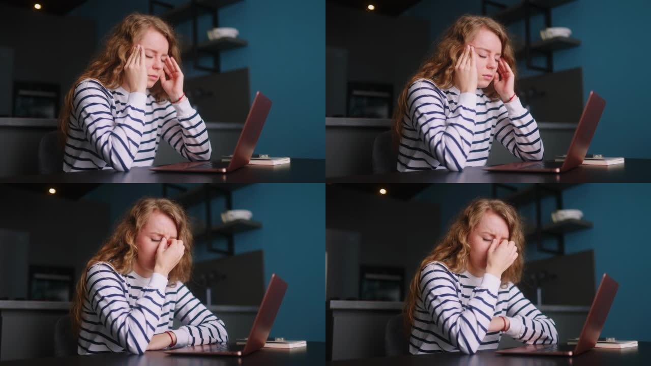 过度劳累的女人在家用笔记本电脑工作，按摩患有头痛的太阳穴。筋疲力尽的女士在使用电脑远程工作后感到眼睛