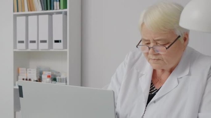 经验丰富的女医生在笔记本电脑中检查患者病史。