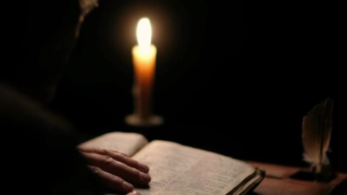 烛光下，老和尚在黑暗的修道院牢房里读旧书的视频。