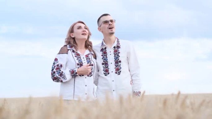 一对穿着民族服装的美丽乌克兰夫妇在麦田里唱歌。幸福的家庭