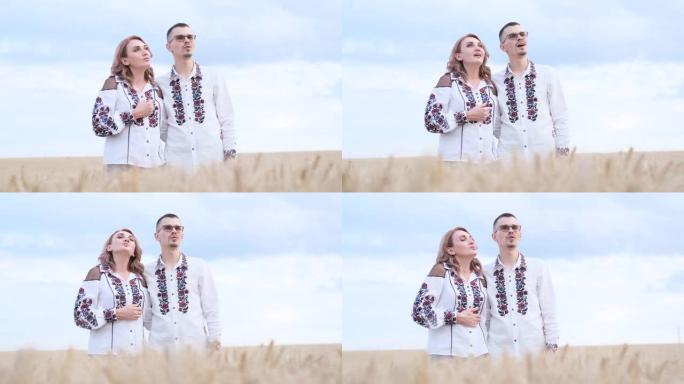 一对穿着民族服装的美丽乌克兰夫妇在麦田里唱歌。幸福的家庭