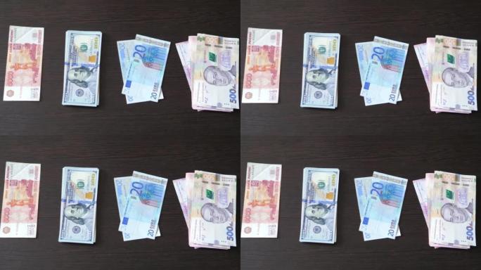 四叠钞票位于棕色的桌子上，美元，欧元，格里夫纳，卢布。现金钞票。金融、投资、货币兑换、贿赂或腐败的概