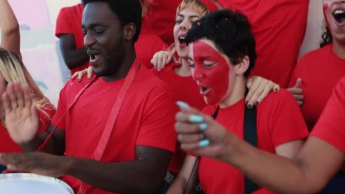 多种族的红色运动迷在支持他们的球队时尖叫-足球支持者在比赛中玩耍-冠军和获胜概念