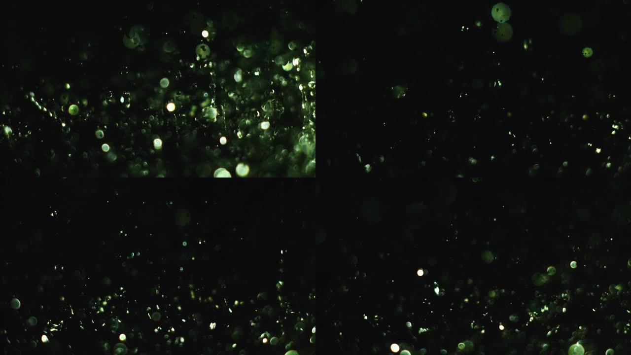 绿色霓虹灯照亮的飞溅水的超慢动作。振动下降分离并反弹成单独的元素。表面张力