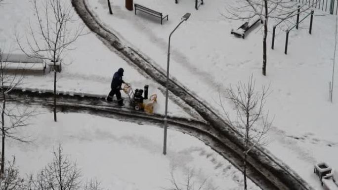 工人在城市院子里用吹雪机除雪