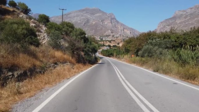 在夏天的一天，在山路上驾驶汽车。希腊克里特岛。汽车租赁和旅行概念。后视摄像头。