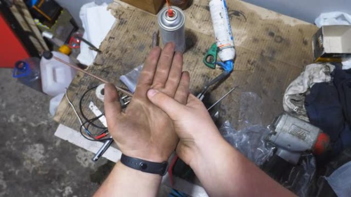 车间里年轻机械师的男性脏手。修理工在车库辛苦工作后，用燃油摩擦不干净的手臂。维护服务的概念。慢动作