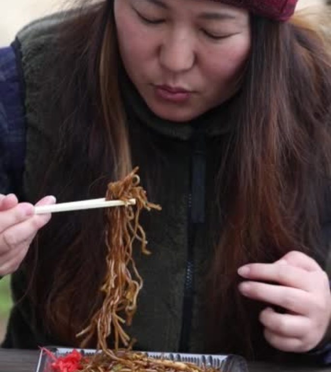 一个女人在户外的节日里吃日本烤肉串