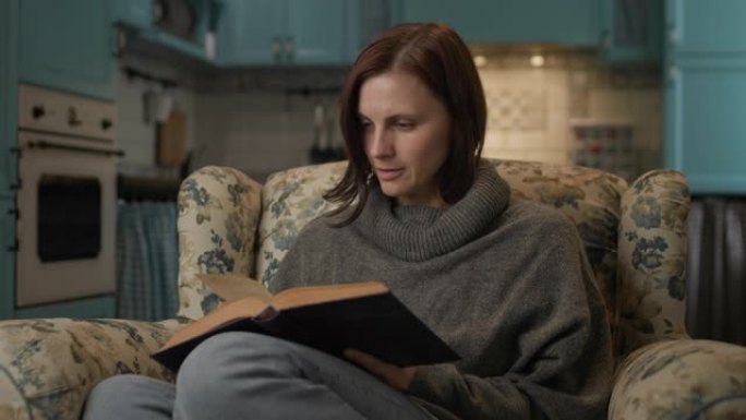 女人读纸质书。30多岁的女性喜欢坐在家里舒适的沙发上阅读文学作品。