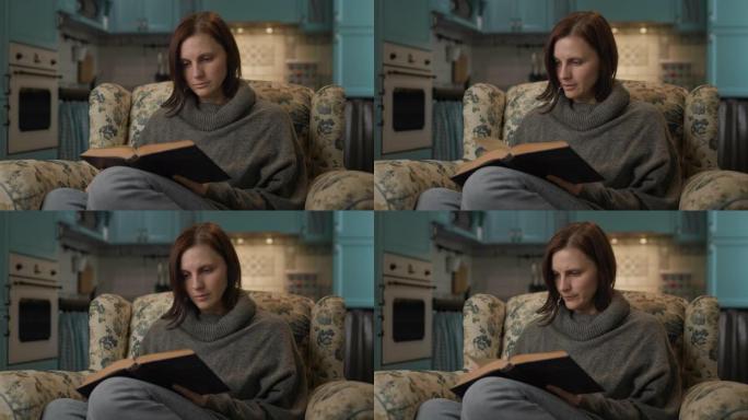 女人读纸质书。30多岁的女性喜欢坐在家里舒适的沙发上阅读文学作品。