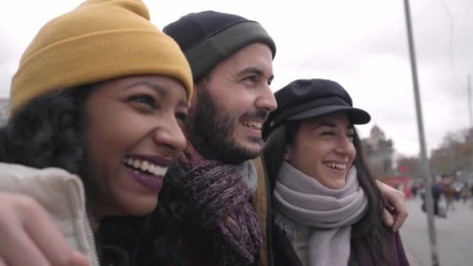 在伦敦拥抱快乐的多种族朋友的特写。与多元文化的年轻人一起穿着冬装的友谊概念。