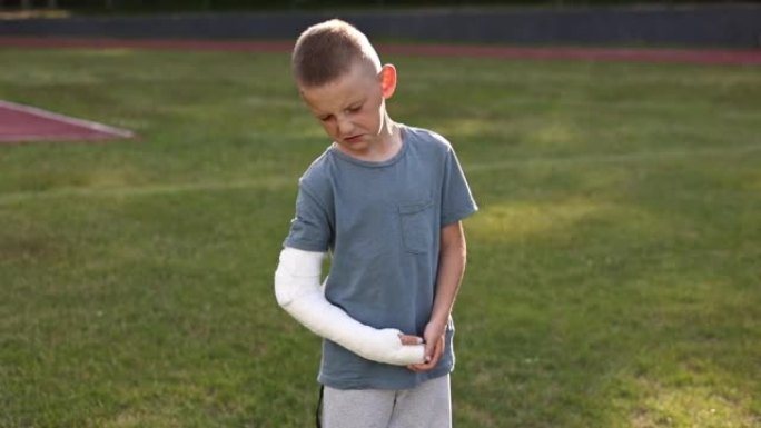 夏天在户外四肢骨折的悲伤小男孩。一个孩子的胳膊断了。骨折损伤。手臂上的石膏