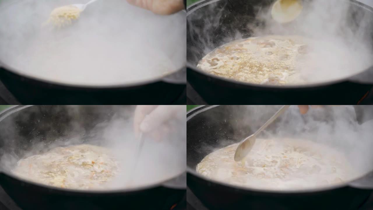 厨师撒上一勺抓饭的调味料，然后在铸铁大锅中煮熟。