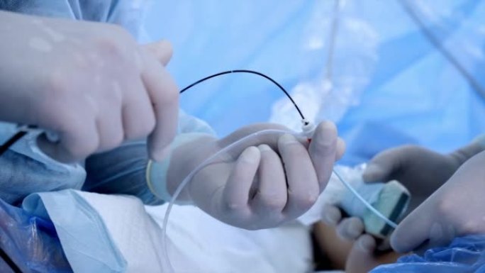 男性戴着手套的手握着并使用手术工具和装置。特写。血管手术正在进行中。