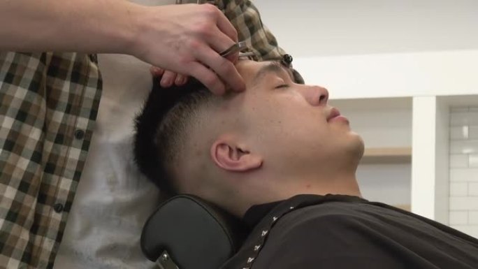 理发师用直剃刀修剪客户的发际线