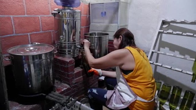 在当地一家小型酿酒厂工作的妇女熟练地手工装瓶葡萄酒