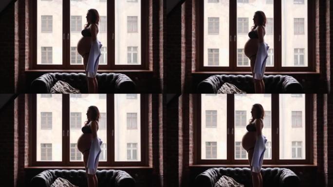 怀孕之美 -- 年轻女性剪影留在明亮的窗户旁