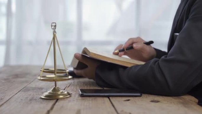律师事务所的概念在线法律咨询和法律咨询。律师法官坐在桌上，拿着纸质智能手机和锤子司法4K
