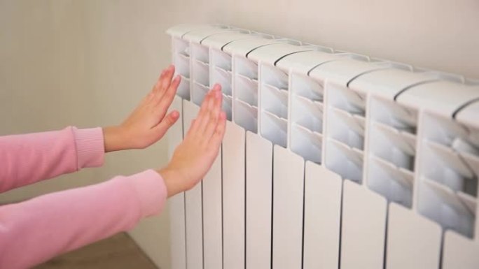 孩子在加热器附近暖手。