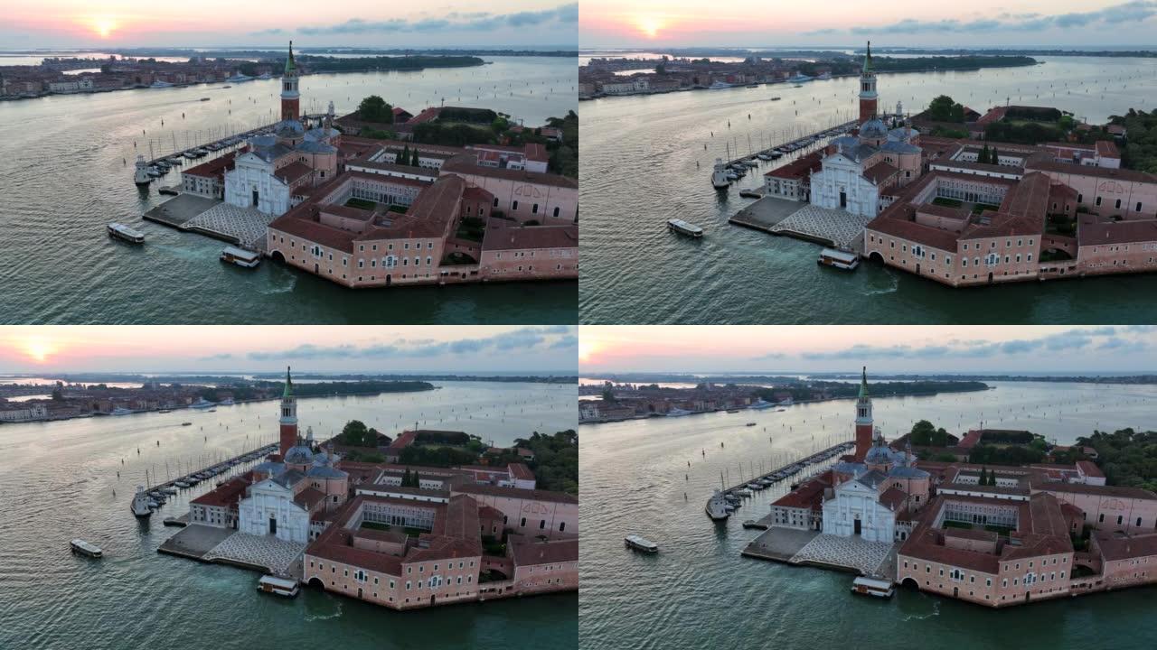 威尼斯群岛圣乔治·马焦雷教堂的空中无人机日出场景和泻湖蓝水之间的船只交通
