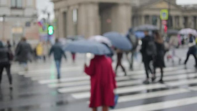 一群人在城市的街道上匆匆忙忙，雨中打着雨伞的人
