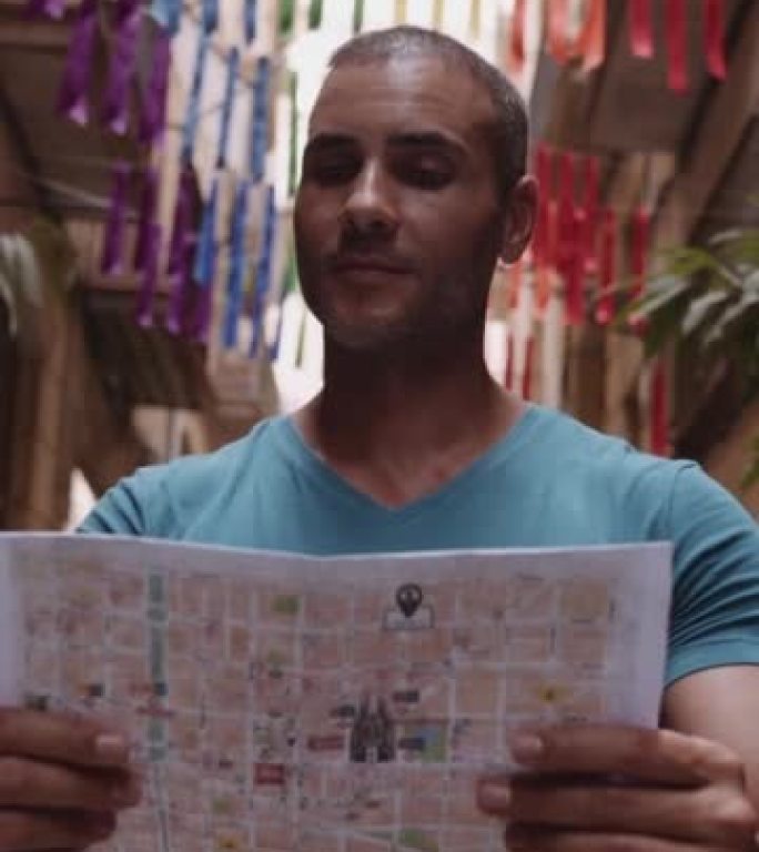 快乐男性旅游地图用户在老城小巷散步，使用地图。西班牙巴塞罗那。垂直视频。