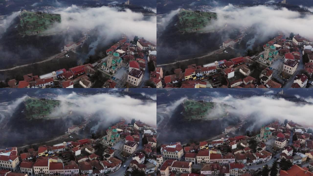4k，黎明时分在Veliko Tarnovo的鸟瞰图。秋天和雾低垂。低头看着云。房屋和教堂进入小镇