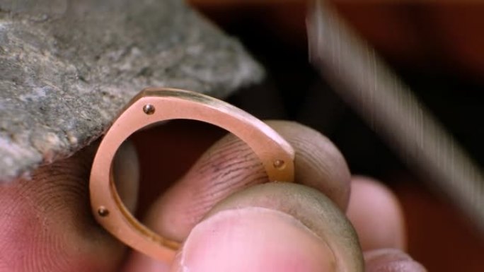 金匠正在打磨一枚金戒指。珠宝商在珠宝车间工作