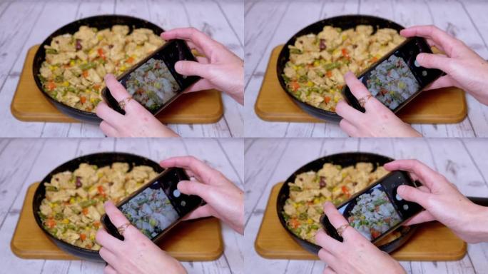 女性在智能手机相机上拍摄蔬菜炒肉的照片