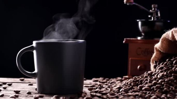 杯子里有天然咖啡烟雾的热饮料。一个热咖啡杯的特写镜头，自然蒸汽上升，黑色背景下的古董研磨机，4k。餐