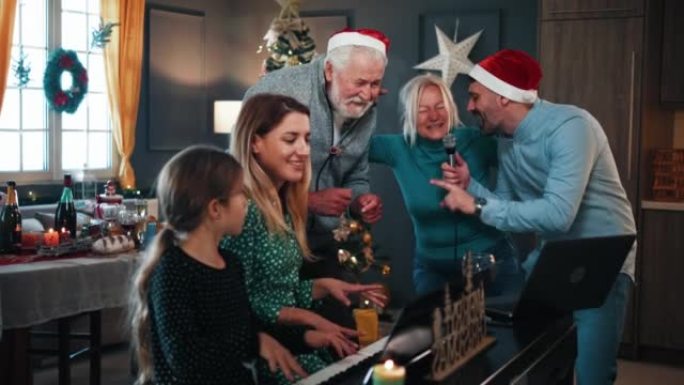 快乐家庭在家里的圣诞晚会上唱卡拉ok和弹钢琴