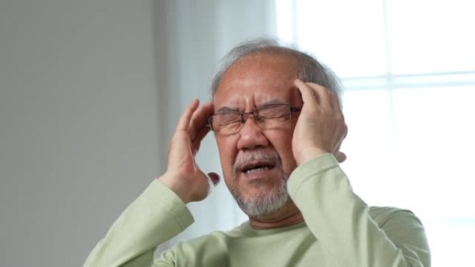 亚洲老年老人在家里的客厅感到头痛和偏头痛。强调成熟男性伤害精神卫生护理和保险理念。