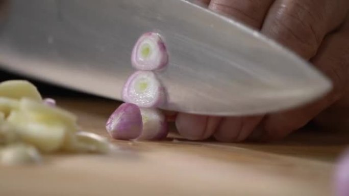 由专业厨师用菜刀将小葱，红洋葱在木制切菜板上切成薄片。