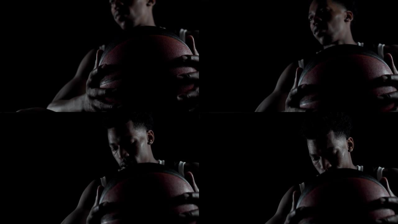 篮球运动员坐在长凳上深吸一口气，往下看。黑人背景下的非裔美国体育人。