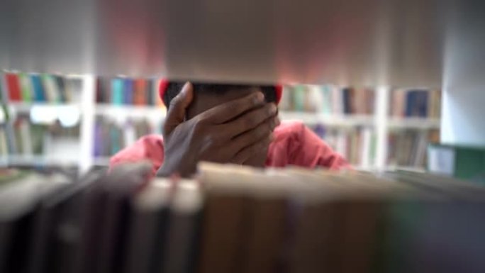 疲惫焦虑的黑人学生站在书架之间，在大学图书馆找不到书