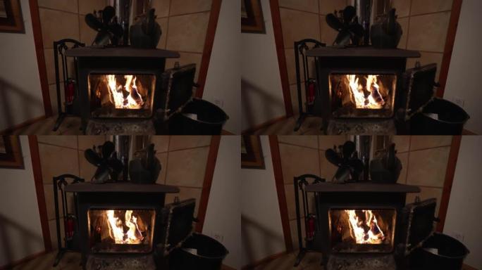 带热扇和铁水壶的柴炉壁炉的广角视图。慢动作中的火