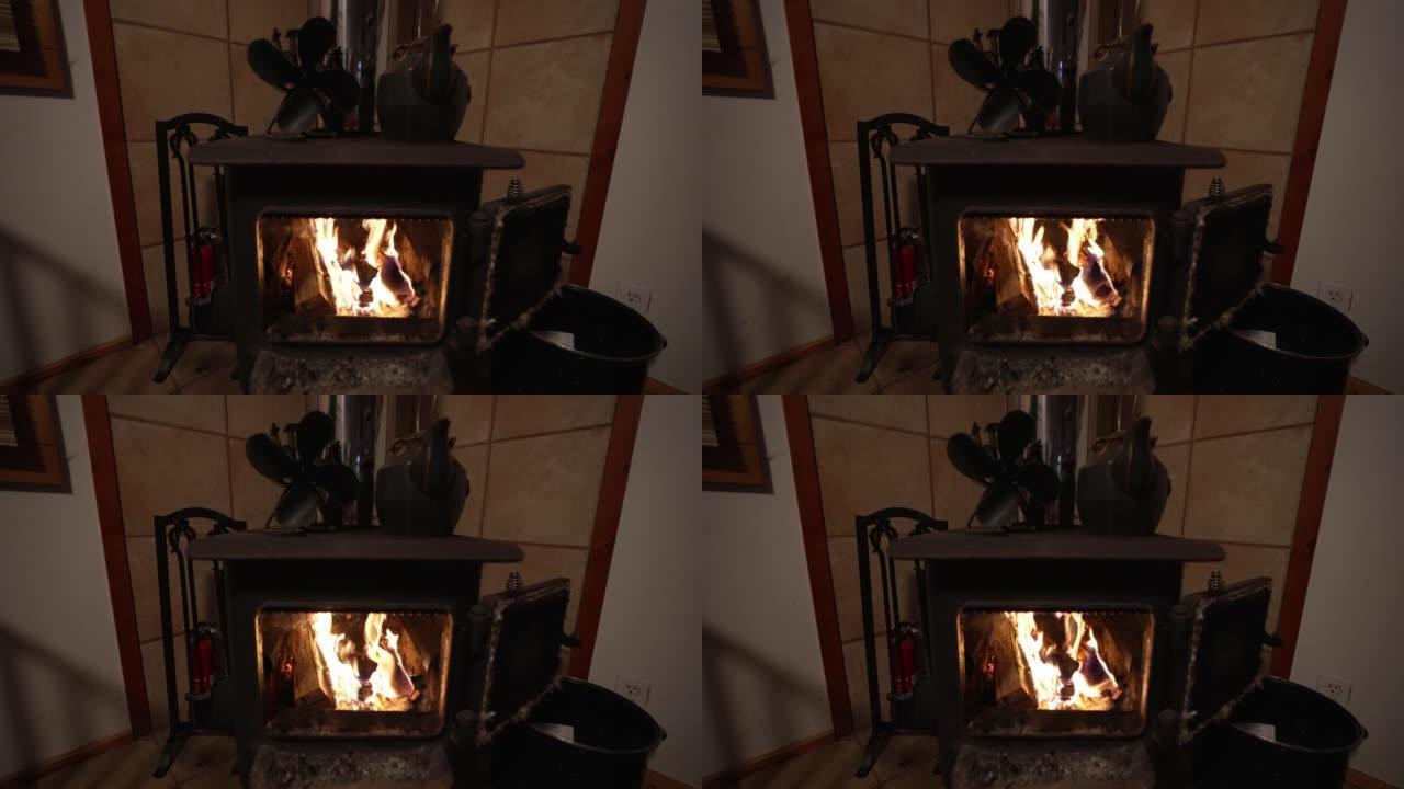 带热扇和铁水壶的柴炉壁炉的广角视图。慢动作中的火