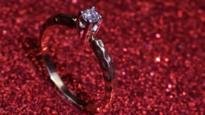 美丽闪亮的金色订婚戒指，闪闪发光的红色背景上有大宝石钻石。情人节礼物。