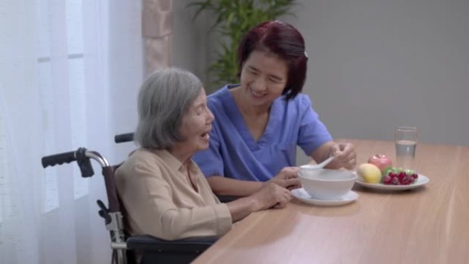 照顾者用汤喂养亚洲老年妇女。