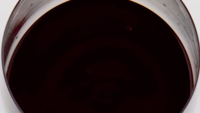 红酒水滴落玻璃特写。圆滑的液体表面波纹
