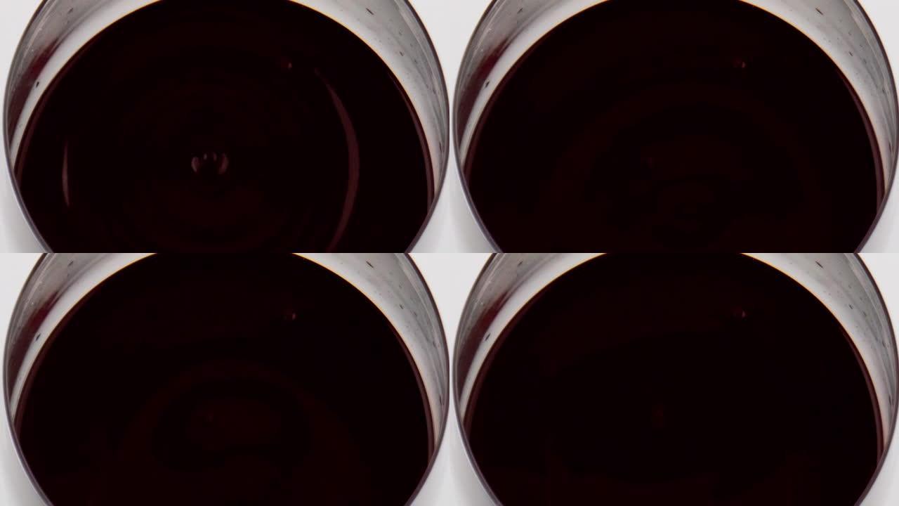 红酒水滴落玻璃特写。圆滑的液体表面波纹