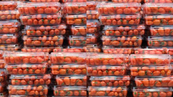 在超市里，成堆的红色樱桃番茄装在塑料容器中。