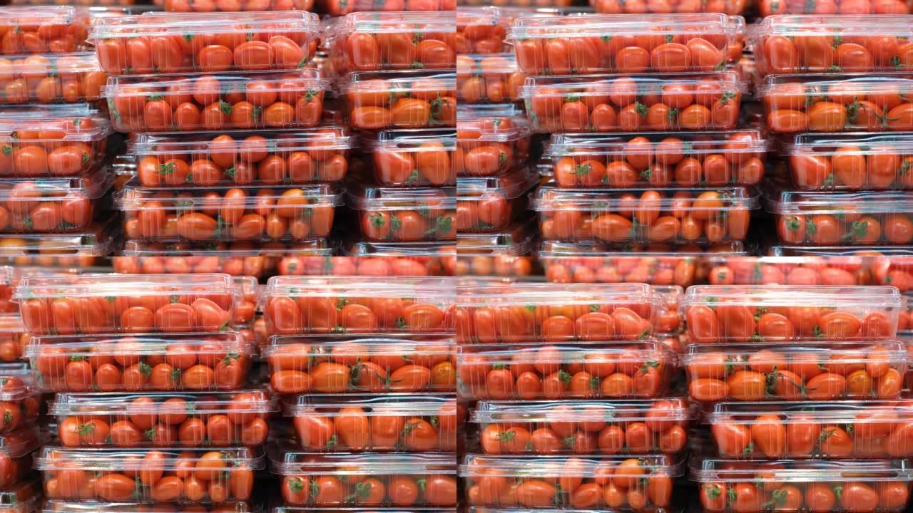在超市里，成堆的红色樱桃番茄装在塑料容器中。