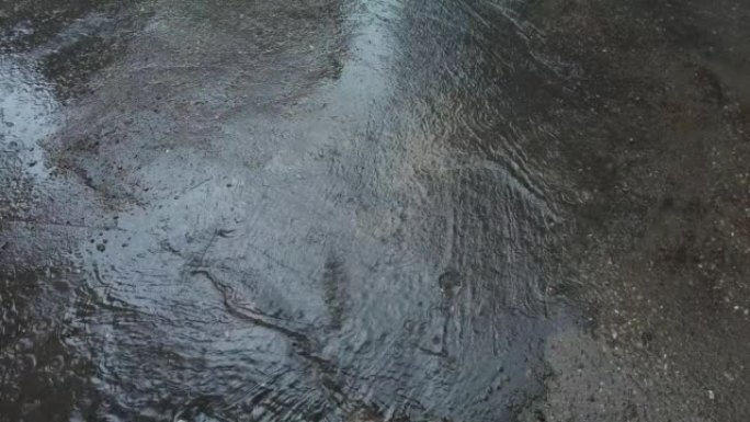 下雨时沥青路面上流淌的小溪。俯视图，慢动作