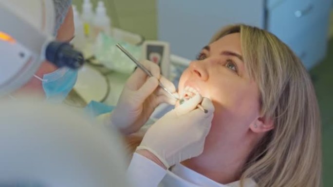 牙医用弯曲的探头检查患者的牙齿，并看着牙镜