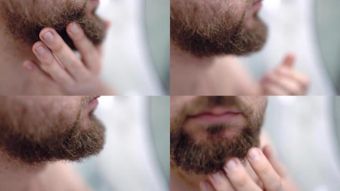男子用手近距离触摸浓密的胡须，男子在镜子前的浴室里每天做面部护肤程序。每日刮胡子作为干燥或受刺激的面