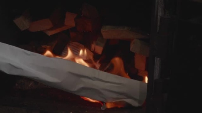 在炉子里，烧纸被带到堆成一堆的柴火上，生火在冬天加热房子。能源和燃料危机导致的替代供暖选择。