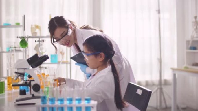 在教室实验室中使用显微镜进行科学实验的女学生