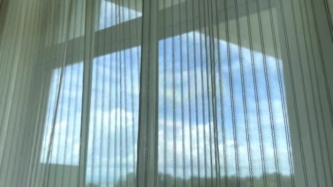 在蓝天上挥舞着白色的窗帘，从酒店阳台的窗户可以看到