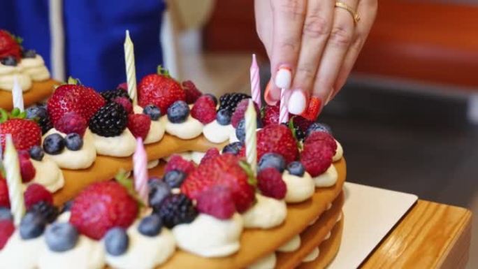 蜡烛以十号的形式放在带有浆果的蛋糕上。